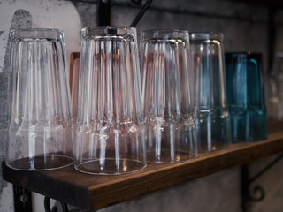 Clean glasses on wooden shelf against grey concrete wall trendy cozy city cafe concept