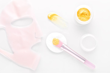 golden facial cream mask with a brush and silicone beauty mask on white background