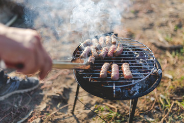 Close up of man preparing kebabs barbecue outdoors. Camping and food concept.
