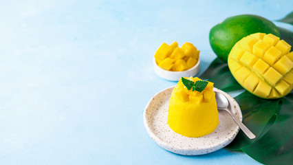 Mango Mousse on blue background with copy space left. Yellow mango mousse with sliced ripe mangoes....