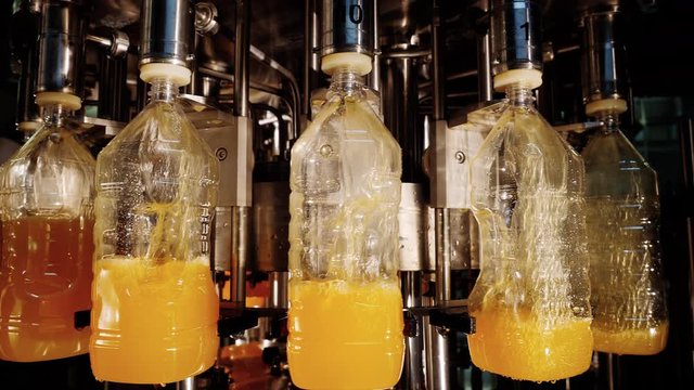 Production automated process for bottling liquids in capacity or plastic bottles on conveyor line of factory using modern industrial metal equipment. Manufacturing line for automation of food industry
