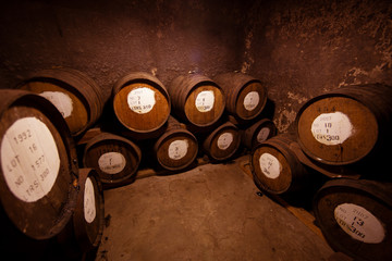 A stack of aging old barrels of cognac in a rustic dark cellar