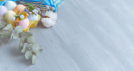 Easter concept. Easter eggs painted in pastel colors in an egg tray with wreaths on them. Light background, place for text.