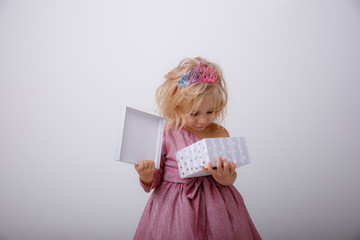 cute little girl in a princess dress with a crown holding a gift on a white background