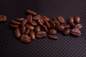 Roasted brown coffee beans on black carbon table or dark background.