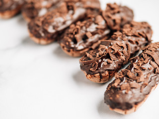 Set of homemade eclairs with chocolate on marble background. Close up view of delicious healthy profitroles with chocolate glaze. Copy space for text or design