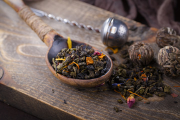 Dry tea leaves on a table in a composition with accessories for tea drinking