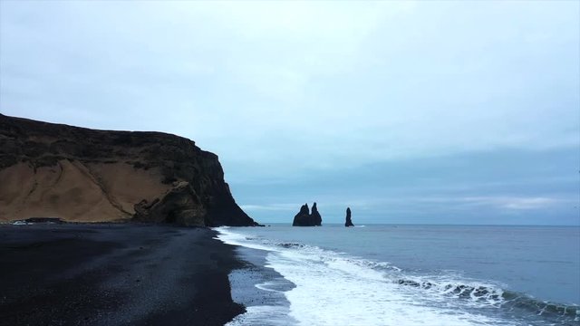 4K Drone Shot Tracking Along The Black Sand Beach In Iceland, By The Sea Violent Waves Over-Cast. Famous Black Sand Beach In Iceland South Of Iceland, Cloudy Day.