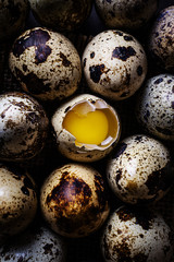 Obraz premium Quail eggs, one opened, the rest whole. Dark background, burlap. View from above. The concept of organic natural products, protein food.