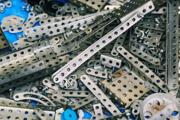 Metal constructor. The iron parts of the steel-colored designer are scattered on the table. Kids metal designer kit for modeling
