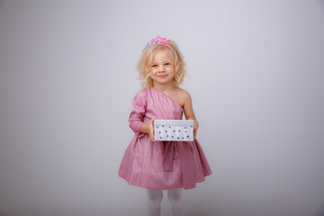 cute little girl in a princess dress with a crown holding a gift on a white background