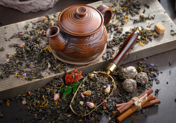 Dry tea leaves on a table in a composition with accessories for tea drinking