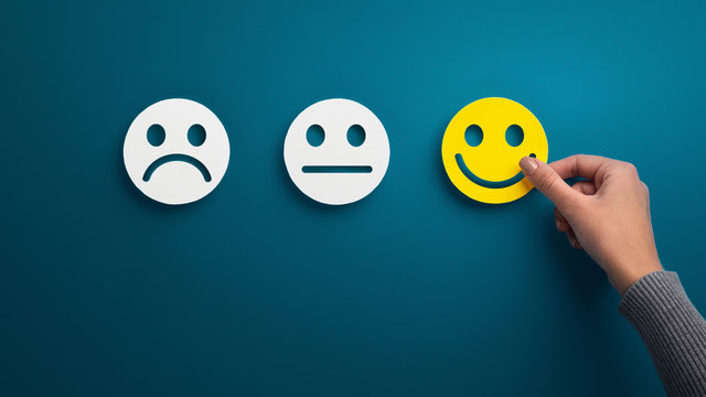 Hand choose the happy smile icon over blue background