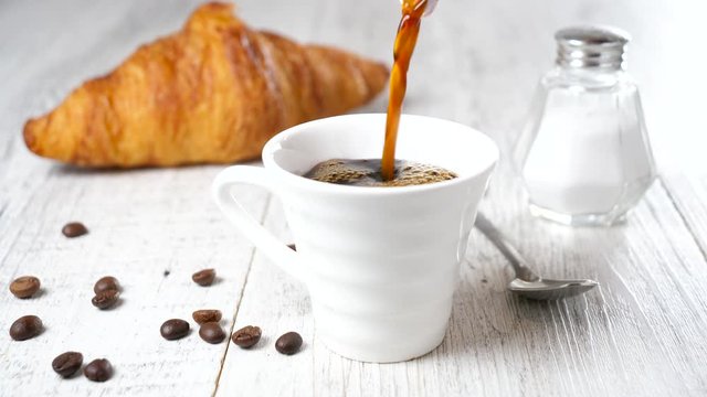 coffee pouring in a cup with croissant- 4K