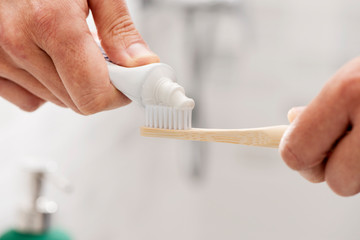 man using a bamboo toothbrush in the bathroom