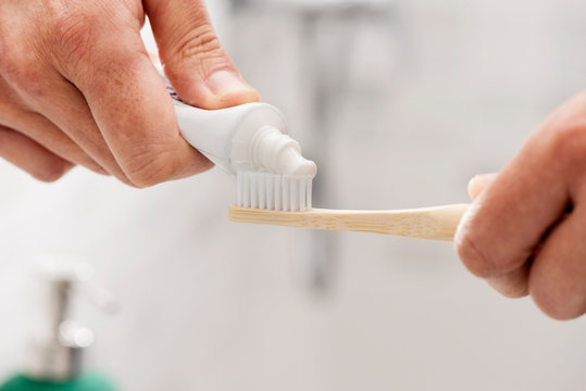 Man Using A Bamboo Toothbrush In The Bathroom