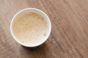 Cappuccino with a delicious foam in a paper cup, top view, coffee to go