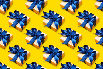 Pattern of trendy attractive gifts with blue bow on the orange background. Merry Christmas, St. Valentine's Day, Happy Birthday and other holidays concept.