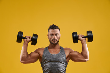 Obraz na płótnie Canvas Handsome bodybuilder working out with dumbbells