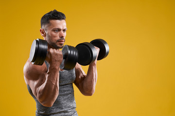 Fototapeta na wymiar Muscular bodybuilder doing exercise with dumbbells