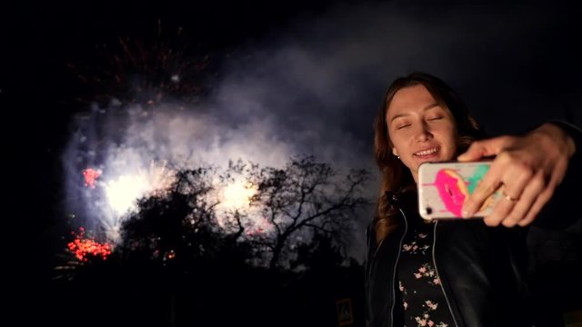 A girl makes selfie on phone during a firework in the night sky. slow motion