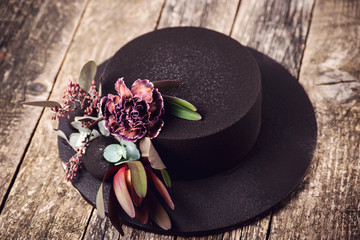 Modern mousse black color cake. Chocolate velour cake with floristic decoration on wooden board.