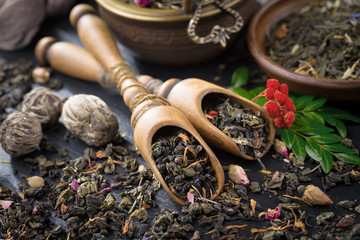 Dry tea leaves in a spoon, on an old background 