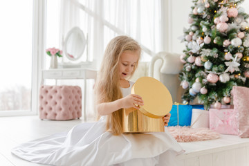 Obraz na płótnie Canvas Little blonde girl opens presents at Christmas.