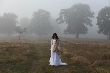 girl in a white dress on a mist field with oaks