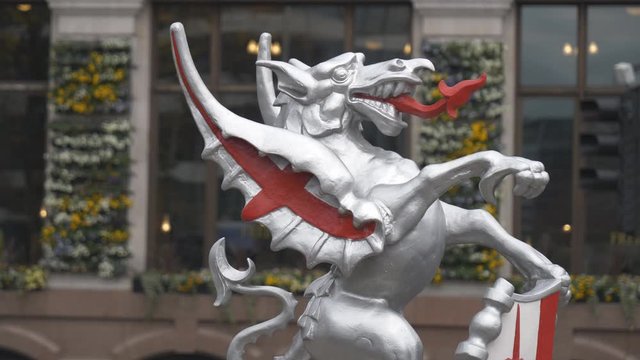 A statue of a silver dragon at a street.