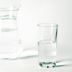 Pure clear water in a glass and jug stands on a white background