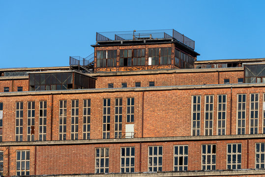 Germany, Saxony-Anhalt, Vockerode: Street view of big old defunct shut down former Vockerode lignite power plant building with brick stone facade, no chimneys and blue sky - concept energy lost place