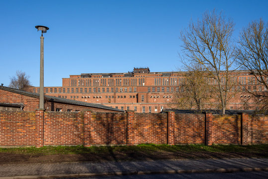 Germany, Saxony-Anhalt, Vockerode: Street view of big old defunct shut down former Vockerode lignite power plant building with brick stone facade, no chimneys and blue sky - concept energy lost place