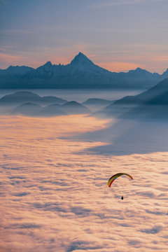 Silhouette of a Paraglider flying above cloud carpet at sunset, Gaisberg, Salzburg, Austria