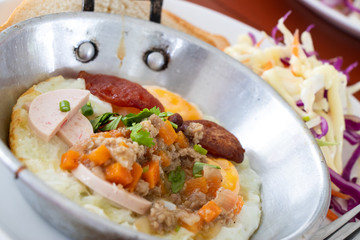 Homemade fried egg, pork chops and Thai sausage in stainless plate background