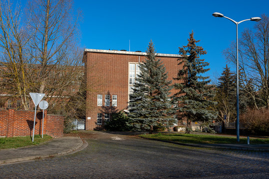 Germany, Saxony-Anhalt, Vockerode: Street view of big old defunct shut down former Vockerode lignite power plant building with brick stone facade, no chimneys and blue sky - concept energy lost place