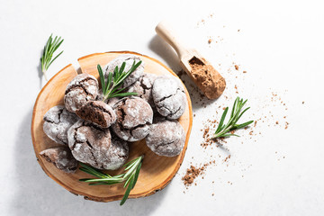 Organic homemade chocolate cookies with aromatic rosemary twigs and cacao powder on the wooden tray. Long banner format. Copy space for your design.