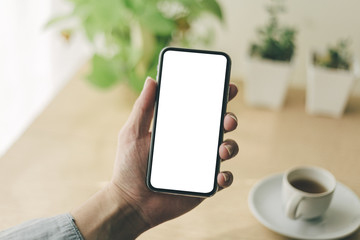 Mockup image blank white screen cell phone.man hand holding texting using mobile on desk at coffee shop.background empty space for advertise text.people contact marketing business,technology 