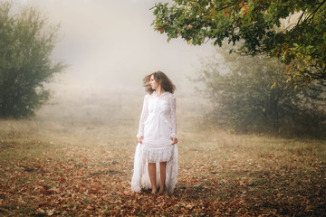 girl in a white dress on a mist field with oaks