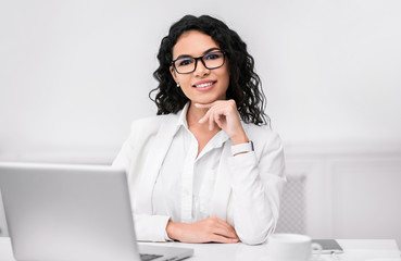 Hispanic manager smiling at camera with hand on chin