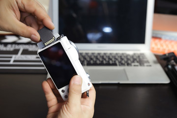 Photographer open the memory card slot cover and Install  inserting  MicroSD Memory Card to digital camera on black desk at studio .selective focus