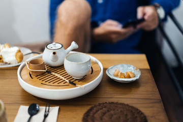 Tea ceremony in an Asian cafe, bamboo table, cup, strainer and teapot.