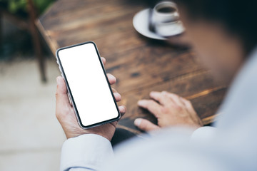 Mockup image blank white screen cell phone.man hand holding texting using mobile on desk at coffee shop.background empty space for advertise text.people contact marketing business,technology 