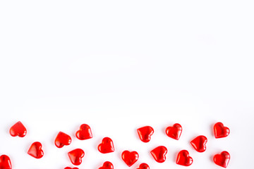Valentine's Day holiday celebration concept. Red glass hearts laid out in the form of a strip along the bottom edge of the image on a white background. Layout with place for your text.