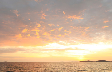 The seaside at sunset has dark shadows in the form of mountains.