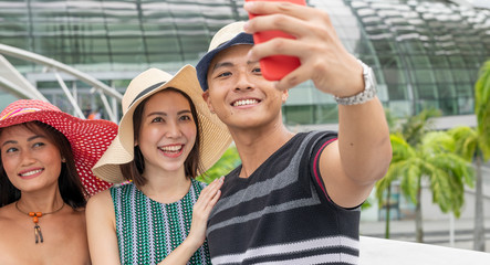 Three mixed genders friends walking along the city taking selfies. Tourism and holiday concept