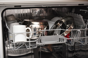 Open dishwasher with clean dishes in the white kitchen