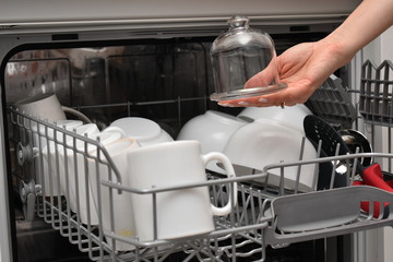 Open dishwasher with clean dishes in the white kitchen