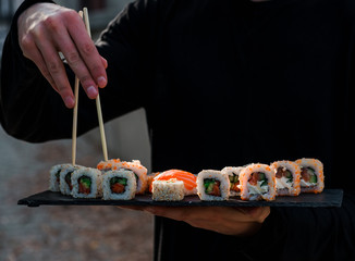 hands hold sushi on blackboard