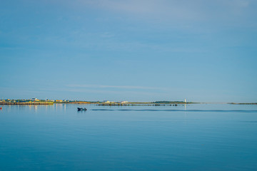 Obraz premium Rocky sea coast shoreline with distant lighthouse.